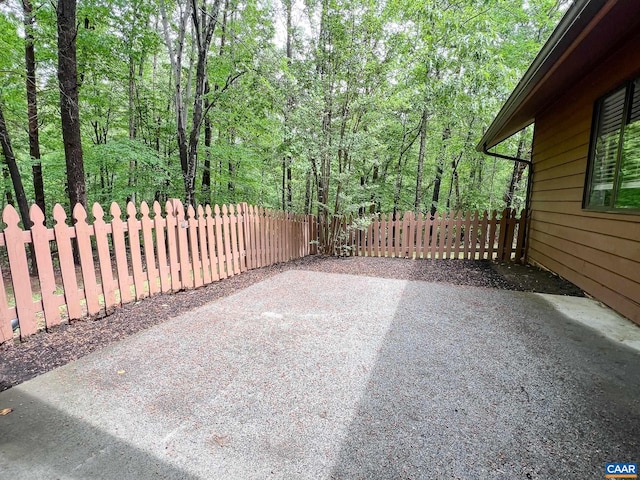 view of patio with fence and a view of trees