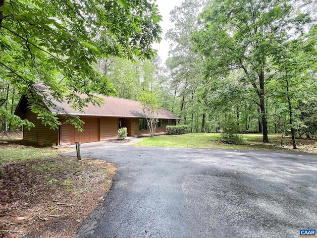 ranch-style house featuring a garage, a front lawn, and aphalt driveway