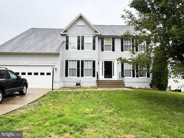 colonial inspired home with entry steps, an attached garage, driveway, and a front lawn