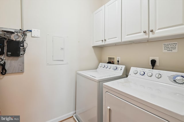 laundry area with washing machine and dryer, cabinet space, electric panel, and baseboards