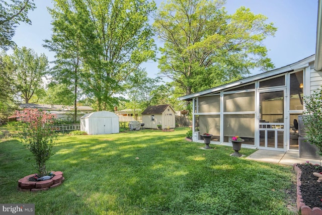 view of yard featuring a storage unit, fence, an outbuilding, and a sunroom