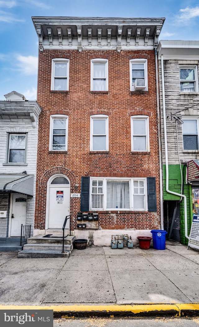 townhome / multi-family property with cooling unit and brick siding