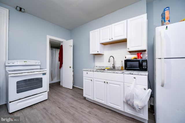 kitchen with a sink, white appliances, backsplash, white cabinets, and light wood-style floors
