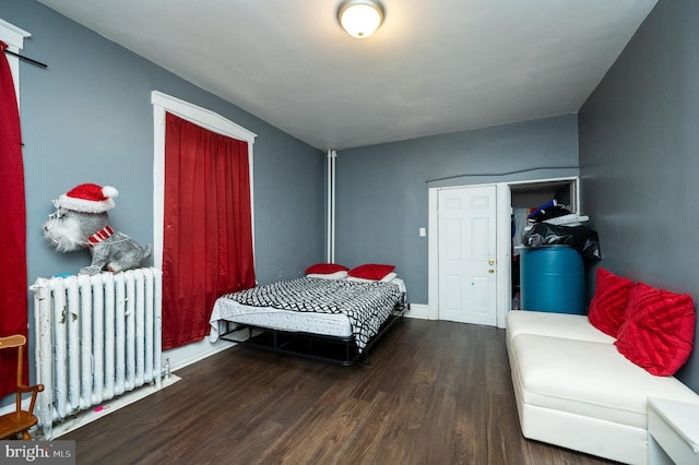 bedroom with baseboards, radiator heating unit, and wood finished floors
