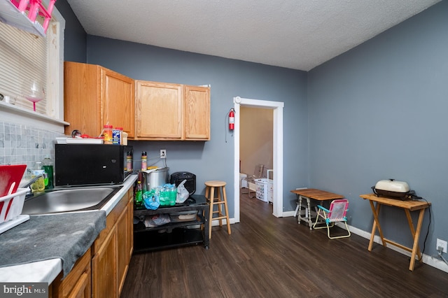 kitchen featuring baseboards, a sink, dark wood-style floors, and black microwave
