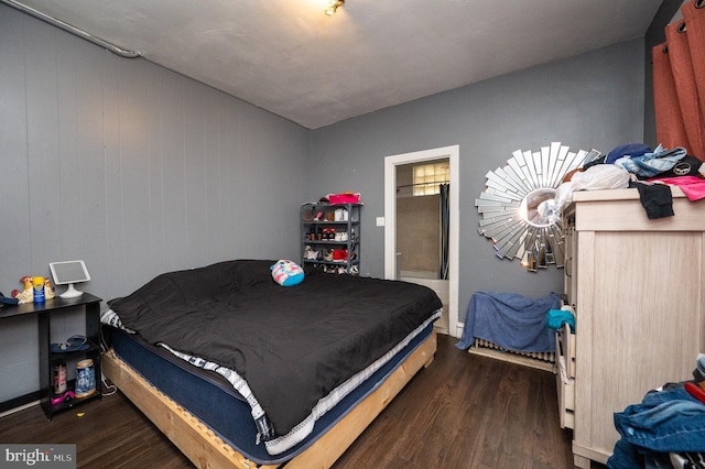 bedroom featuring ensuite bathroom and dark wood-type flooring