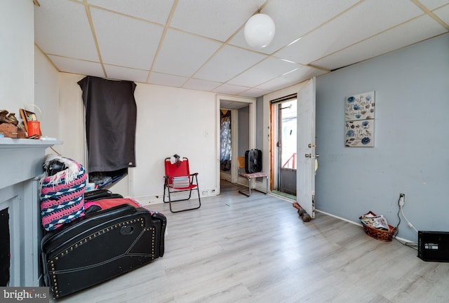 interior space with baseboards, a drop ceiling, and wood finished floors
