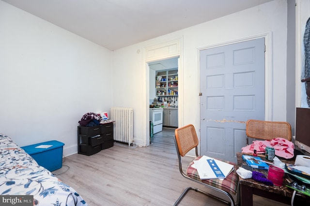 bedroom with radiator, baseboards, and wood finished floors