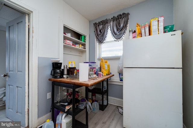 kitchen with freestanding refrigerator, baseboards, and wood finished floors