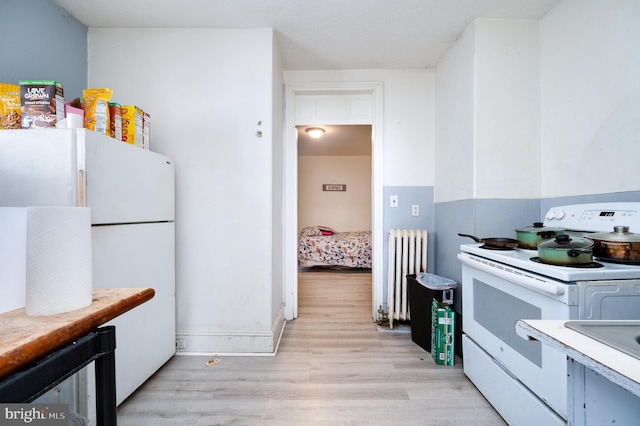 kitchen featuring white appliances, radiator heating unit, wine cooler, light wood-type flooring, and light countertops