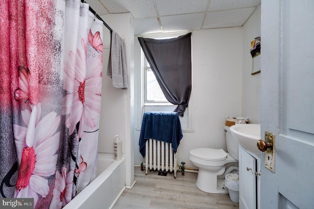 bathroom featuring toilet, radiator heating unit, wood finished floors, vanity, and a paneled ceiling