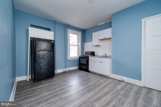 kitchen featuring white cabinets, wood finished floors, black appliances, and a sink