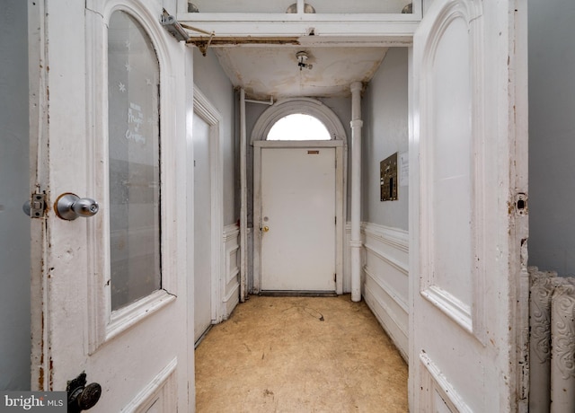 doorway with concrete flooring and a wainscoted wall