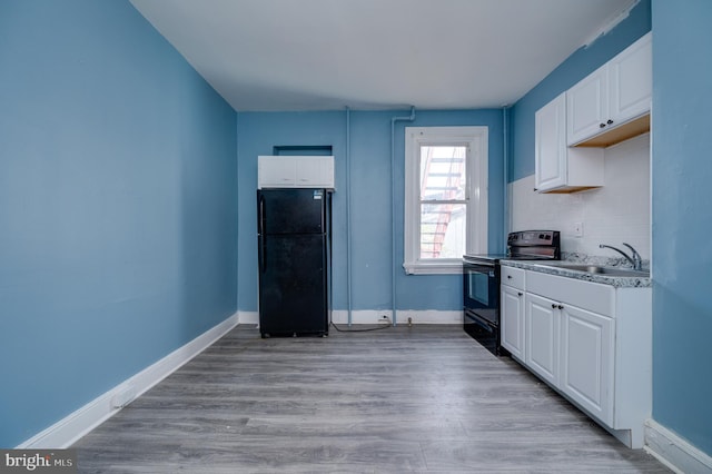 kitchen with white cabinets, baseboards, black appliances, and a sink
