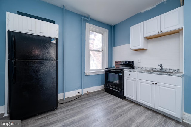 kitchen featuring a sink, light wood finished floors, black appliances, and white cabinets