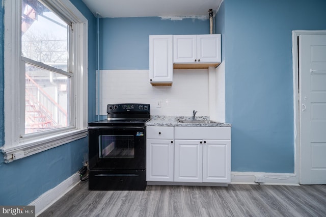 kitchen featuring a sink, a wealth of natural light, black range with electric stovetop, and white cabinets