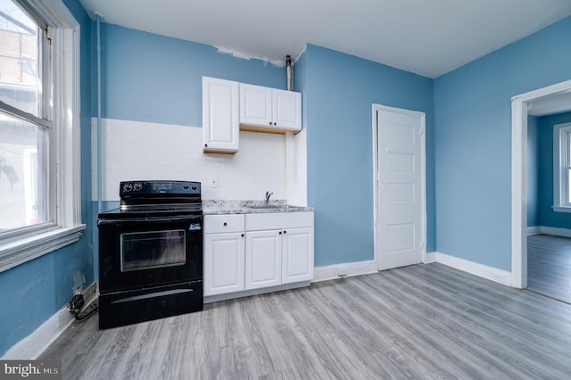 kitchen featuring light wood-style flooring, white cabinetry, plenty of natural light, and electric range