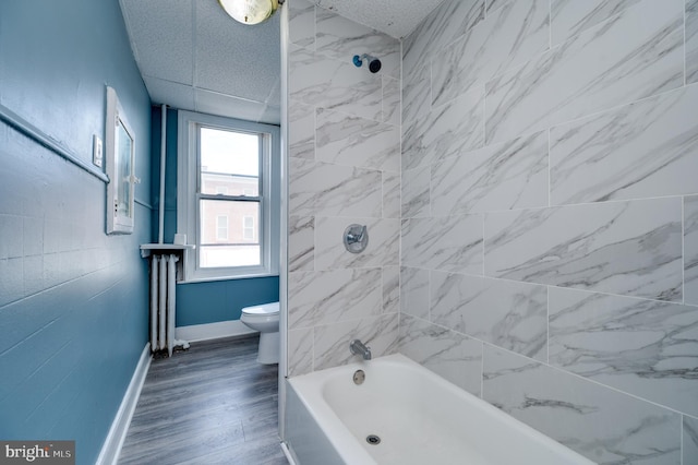 bathroom with shower / bathtub combination, toilet, baseboards, radiator heating unit, and wood finished floors