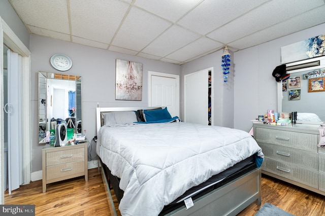 bedroom featuring a closet, a drop ceiling, and wood finished floors