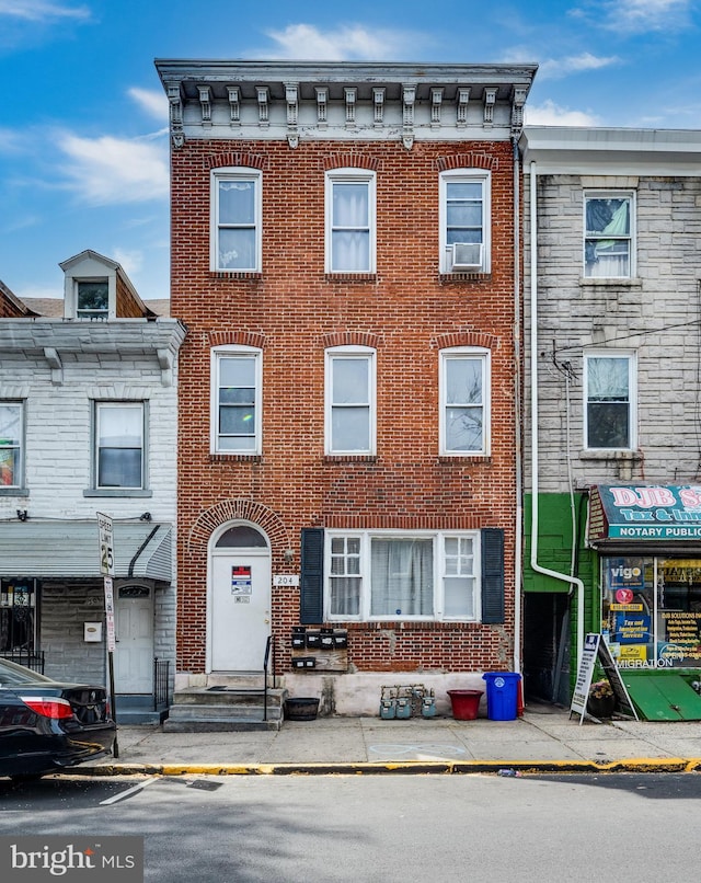townhome / multi-family property with cooling unit and brick siding