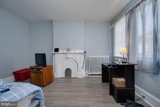 bedroom featuring wood finished floors, baseboards, and radiator heating unit