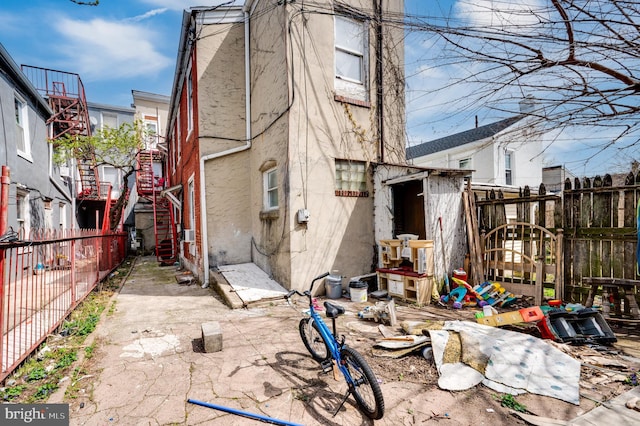 back of house with a storage unit, fence, stucco siding, and an outdoor structure