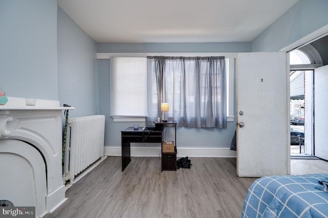 bedroom featuring radiator, baseboards, and wood finished floors