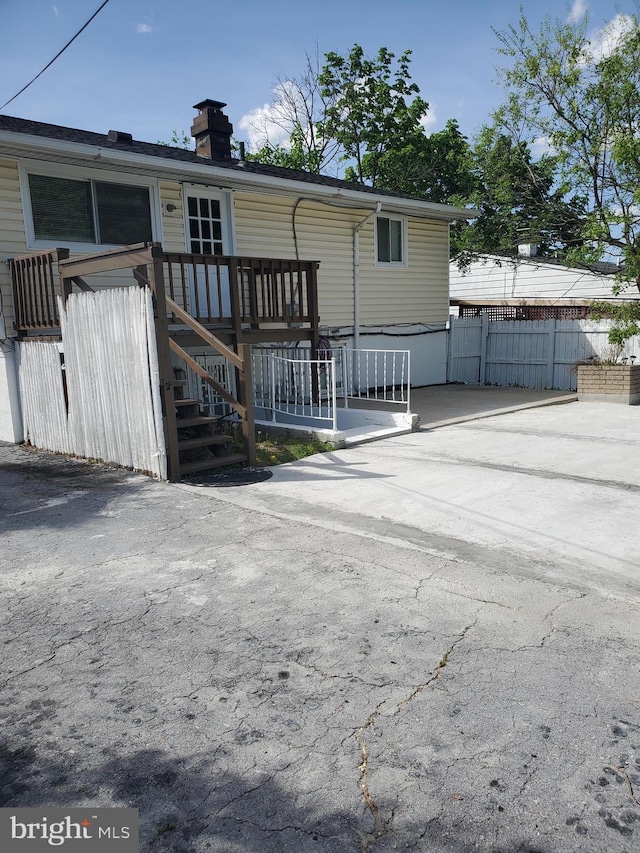 view of front of home with fence, a chimney, and a wooden deck