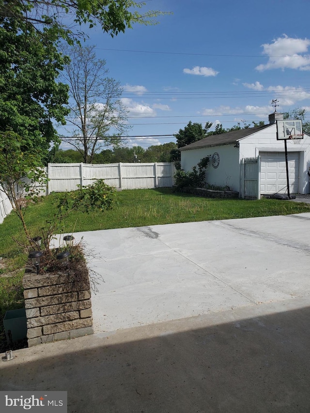 exterior space with a detached garage, fence, and an outbuilding