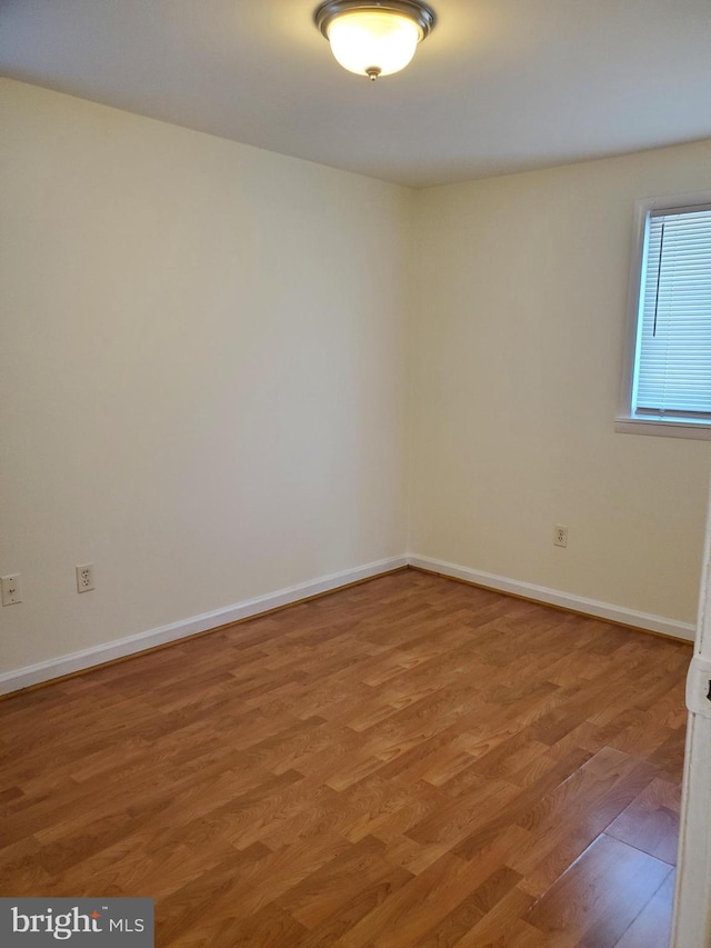 unfurnished room featuring baseboards and light wood-type flooring