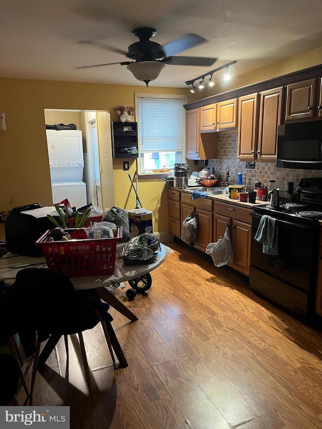217 Federal St, Lebanon, PA 17042 - kitchen with black microwave, stove, stacked washer and clothes dryer, light wood-style flooring, and rail lighting