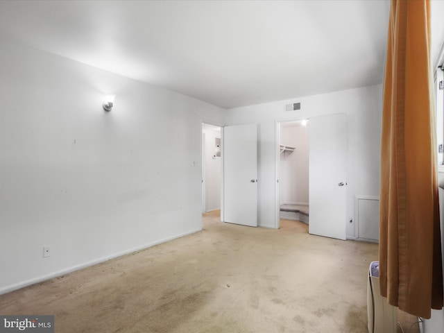 unfurnished bedroom with carpet floors, baseboards, and a walk in closet