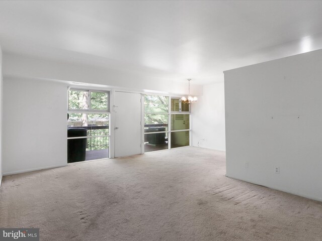 unfurnished living room featuring a chandelier and carpet