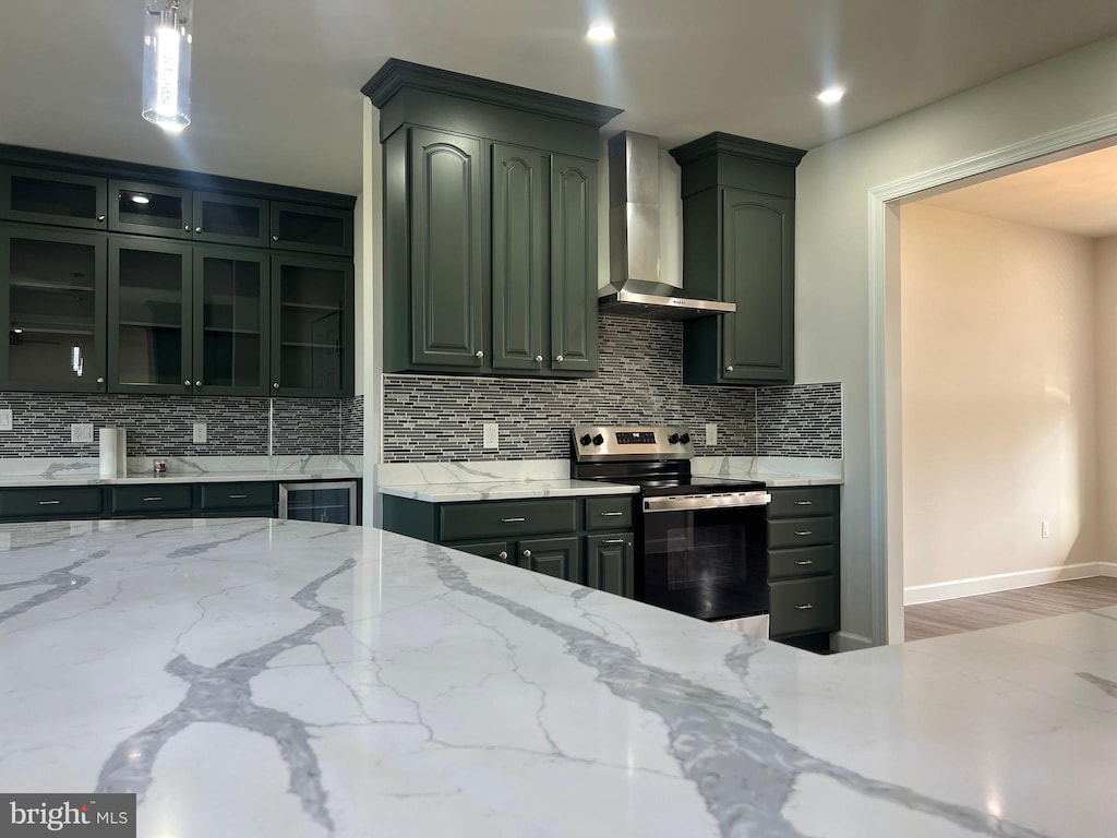 kitchen with wall chimney range hood, backsplash, stainless steel electric range, light stone counters, and wine cooler