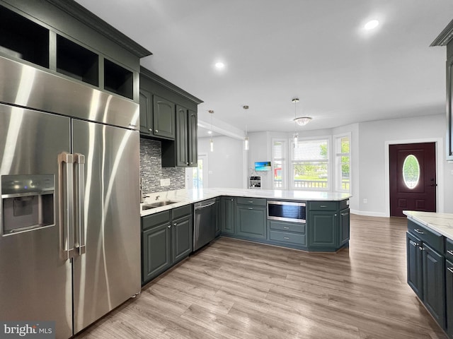 77 Iris Way, Charles Town, WV 25414 - kitchen featuring appliances with stainless steel finishes, light countertops, a peninsula, backsplash, and light wood finished floors