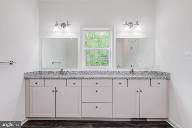 bathroom with a sink, baseboards, double vanity, and wood finished floors