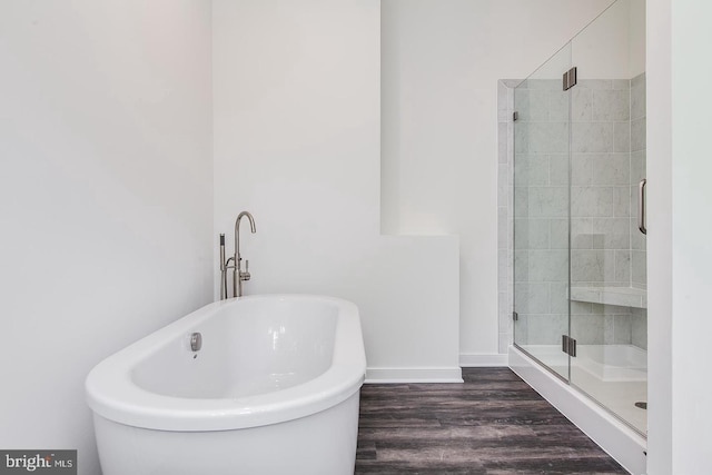 bathroom featuring baseboards, a soaking tub, a stall shower, and wood finished floors