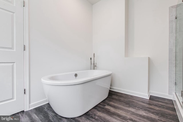 full bathroom featuring tiled shower, baseboards, a soaking tub, and wood finished floors