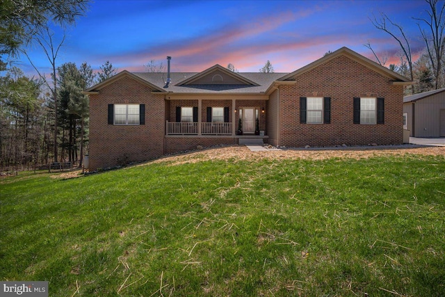 single story home with brick siding, a yard, and a porch