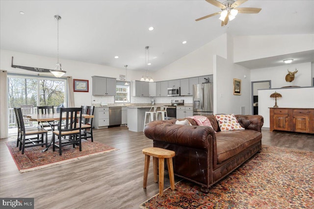 living area with high vaulted ceiling, a ceiling fan, recessed lighting, and wood finished floors