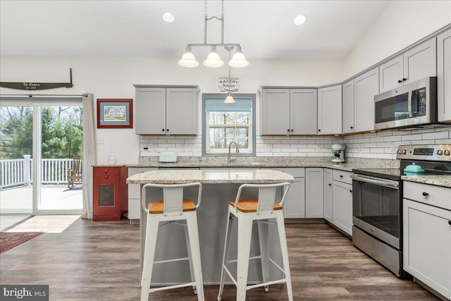kitchen with gray cabinets, tasteful backsplash, a breakfast bar, and stainless steel appliances