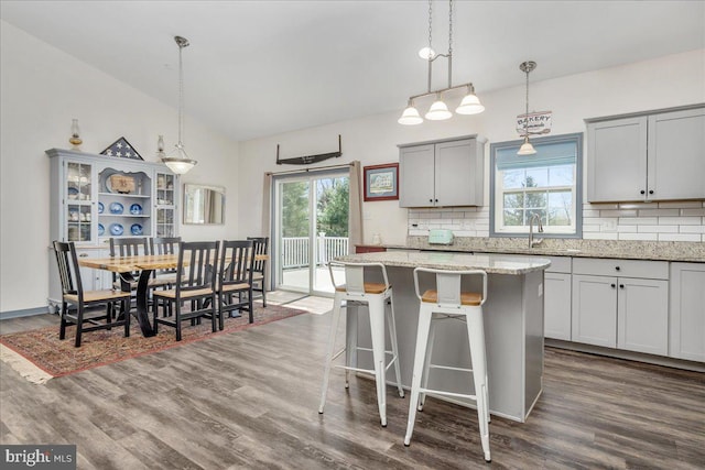 kitchen featuring dark wood-style floors, decorative backsplash, a sink, and lofted ceiling
