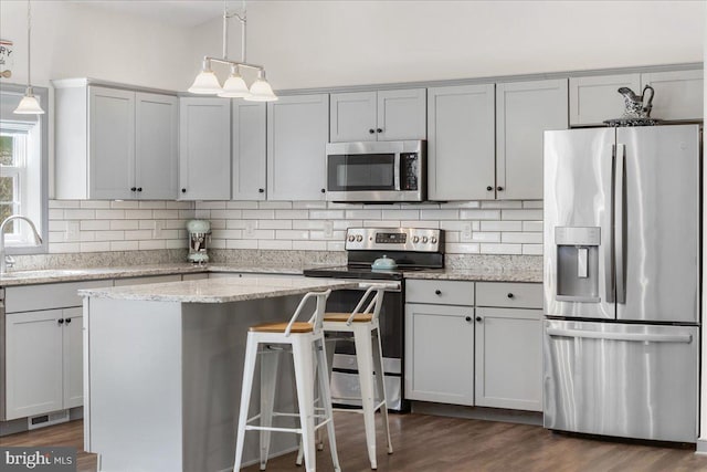 kitchen with hanging light fixtures, stainless steel appliances, decorative backsplash, visible vents, and dark wood-style floors