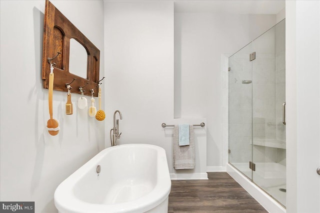full bathroom with wood finished floors, baseboards, a freestanding tub, and a stall shower