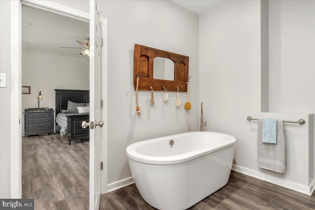 bathroom featuring a freestanding tub, baseboards, a ceiling fan, and wood finished floors