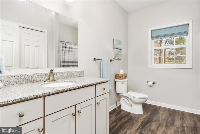 bathroom featuring toilet, baseboards, wood finished floors, and vanity
