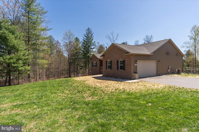 view of side of home with an attached garage, aphalt driveway, central AC, and a lawn