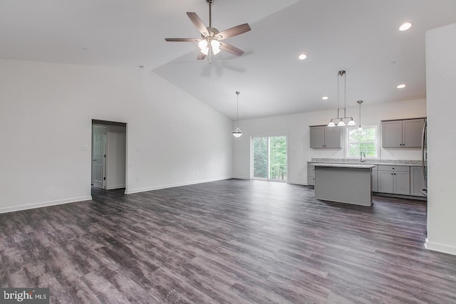 unfurnished living room with high vaulted ceiling, ceiling fan, baseboards, and dark wood-style flooring