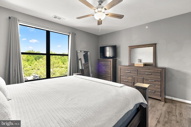 bedroom featuring light wood-style floors, baseboards, and a ceiling fan