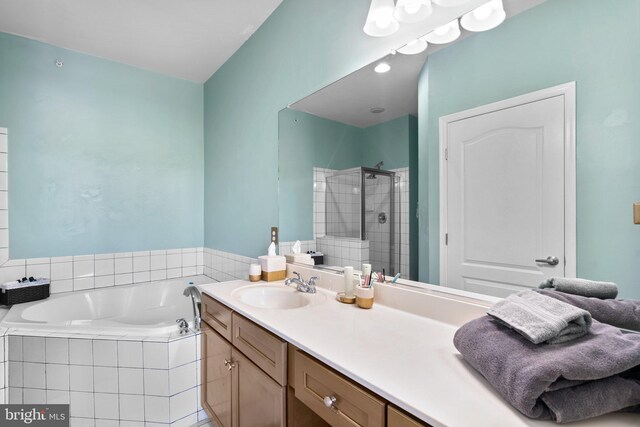 bathroom featuring a shower stall, a bath, and vanity